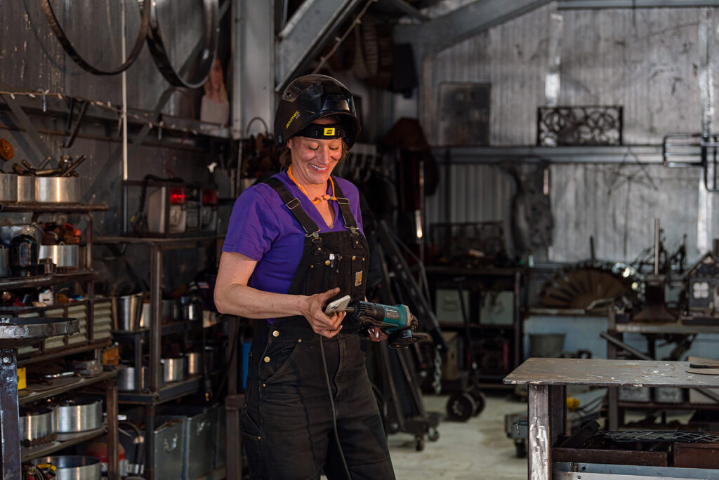 Photo of Jen Kresl in her shop holding a phone